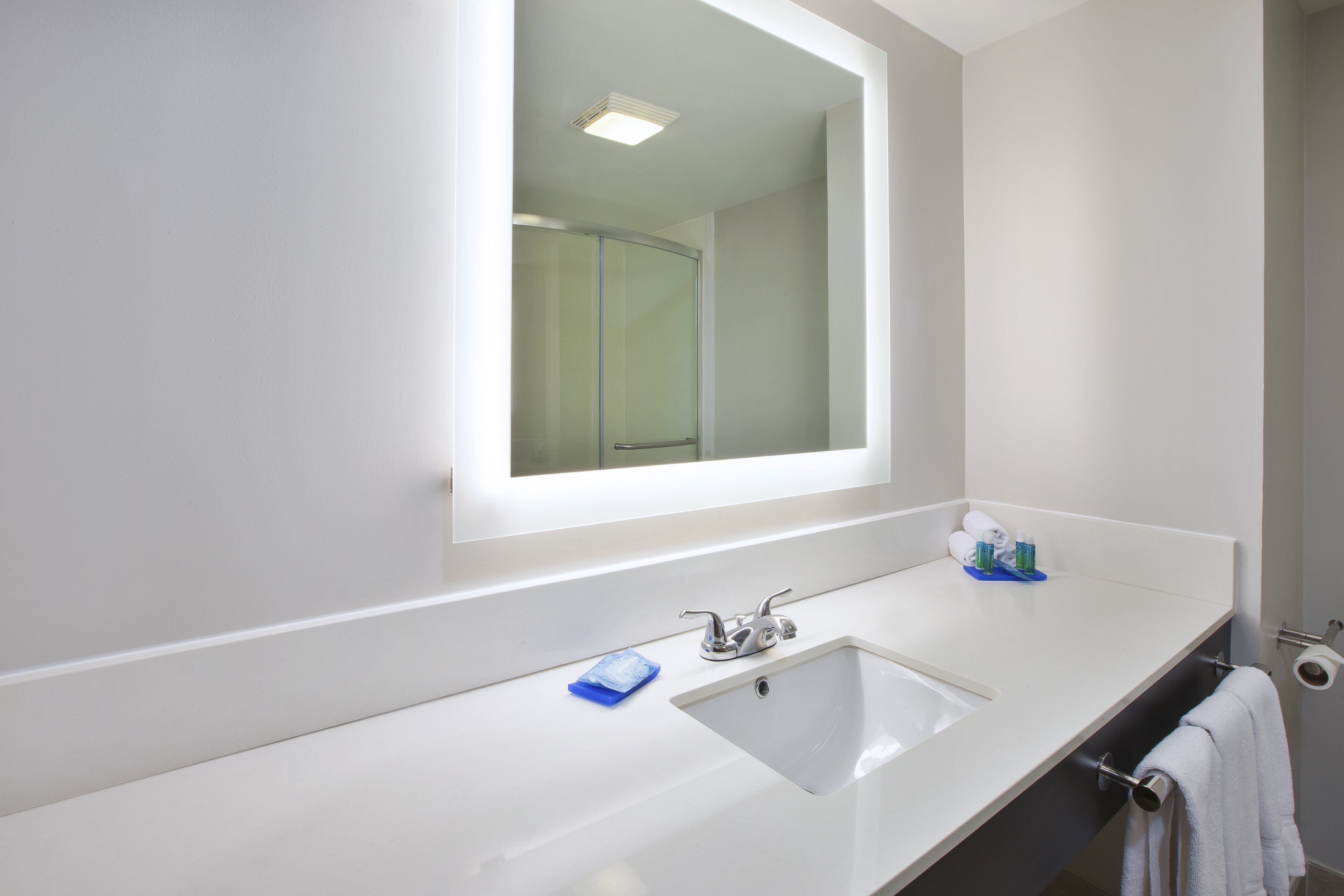 A bathroom with a white sink, a mirror, and a towel rack.