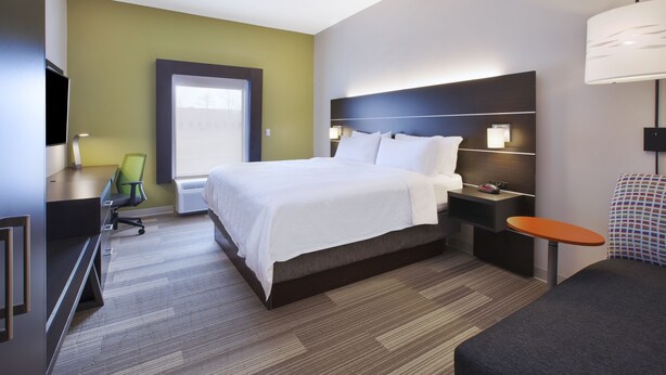 A hotel room with a large bed, a desk with a chair, a nightstand with a lamp, and a TV. - Holiday Inn Express Tiffin by IHG (Tiffin)