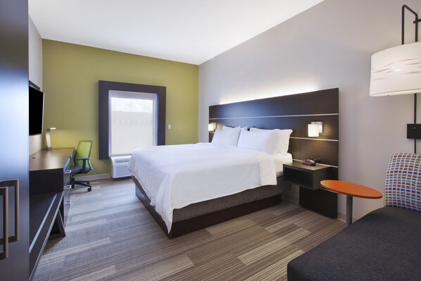 A hotel room with a large bed, a desk with a chair, a nightstand with a lamp, and a TV. - Holiday Inn Express Tiffin by IHG (Tiffin)
