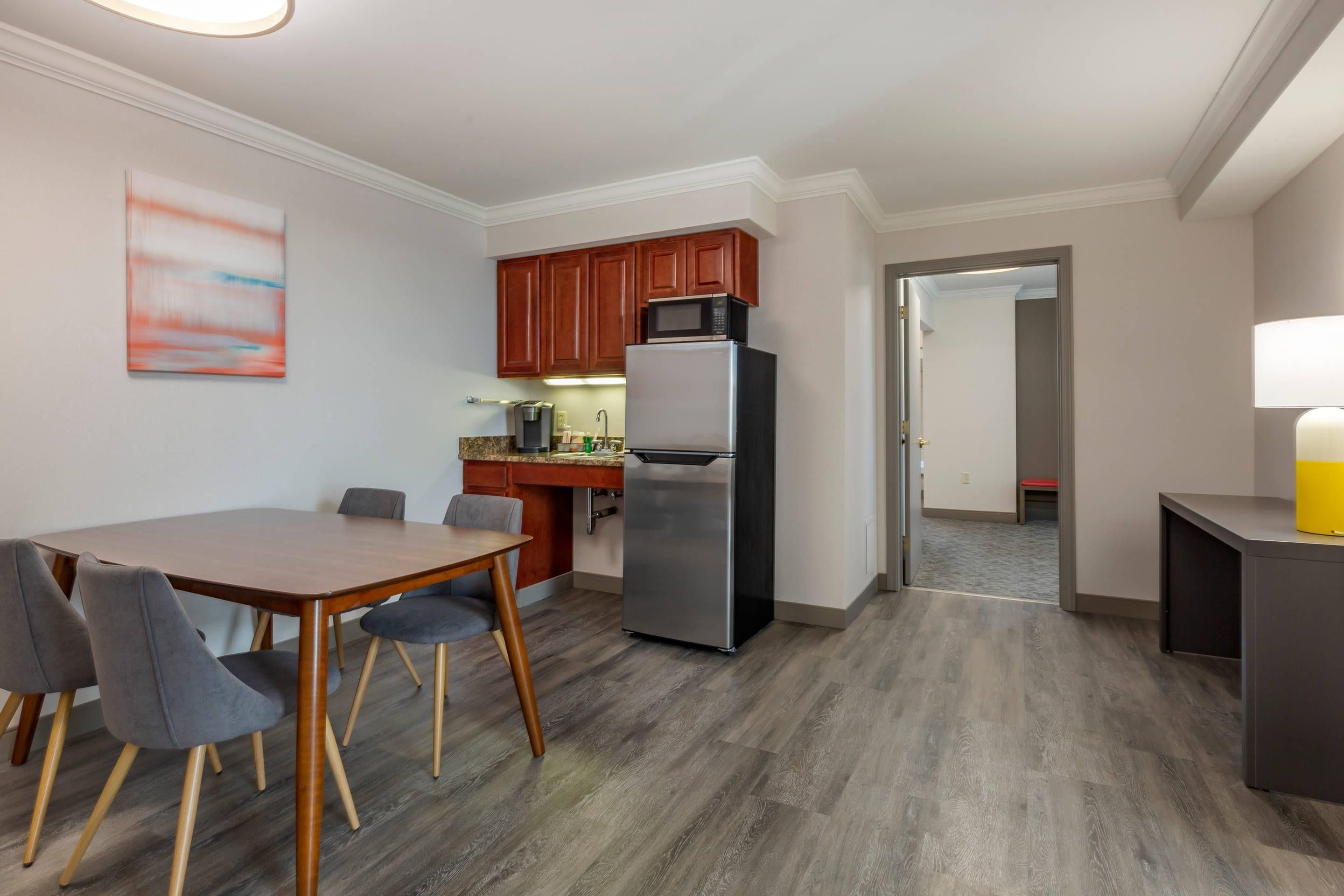 A modern kitchen with a refrigerator, microwave, and wooden cabinets.
