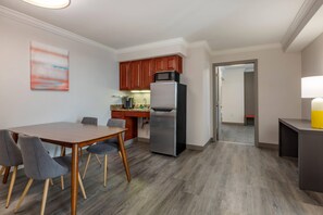 A modern kitchen with a refrigerator, microwave, and wooden cabinets.