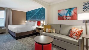 A hotel room with a bed, a sofa, a round coffee table, and a nightstand. - Comfort Inn & Suites Hadley - Amherst (Hadley)