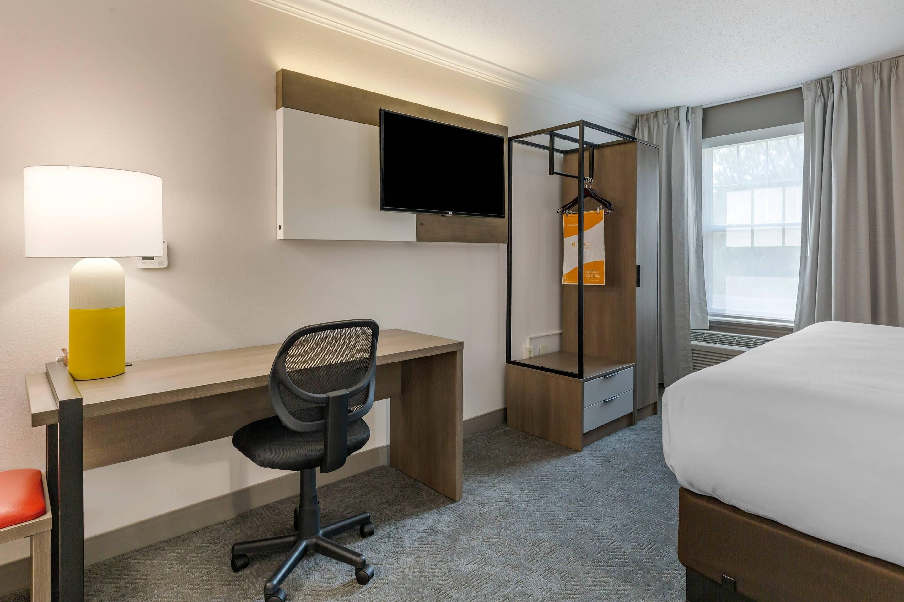 Ein Hotelzimmer mit Schreibtisch, Stuhl, Fernseher und einem Bett.