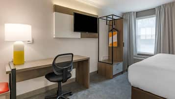Ein Hotelzimmer mit Schreibtisch, Stuhl, Fernseher und einem Bett.