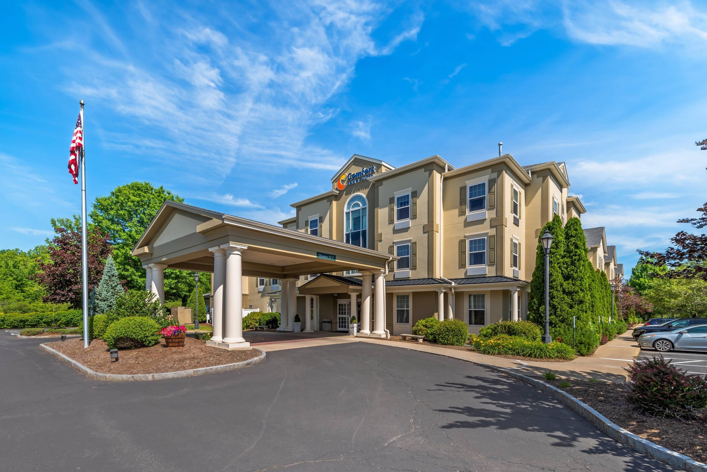 A hotel with a covered entrance, a flag, and a clear sky.