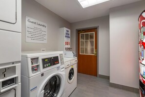 A laundry area with a sign indicating it's for guest use only, a commercial washer, and a door leading to another room.