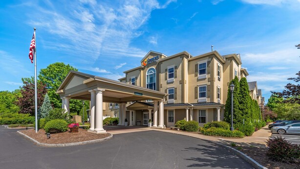 A hotel with a covered entrance, a flag, and a sign. - Comfort Inn & Suites Hadley - Amherst (Hadley)