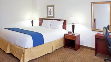Une chambre d’hôtel comprenant un lit, des tables de chevet, un bureau, une chaise et un miroir.