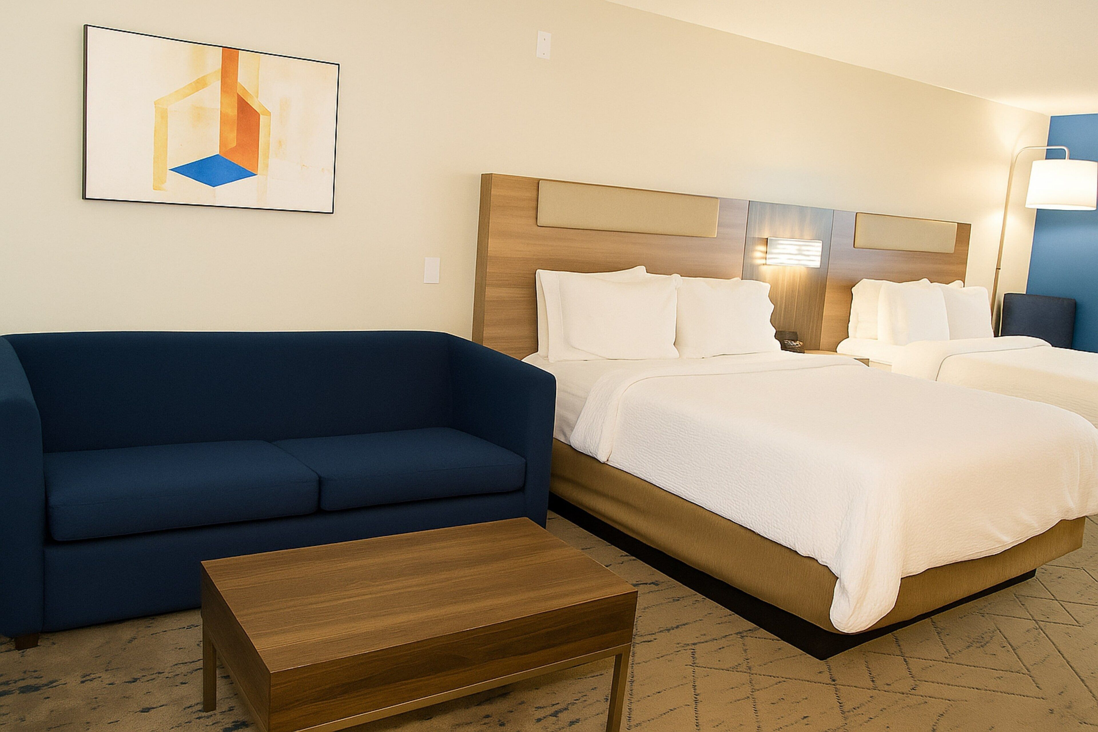 Ein Hotelzimmer mit einem Bett, einem blauen Sofa und einem Holztisch.