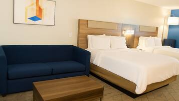 Una habitación de hotel con una cama, un sofá azul y una mesa de centro de madera.