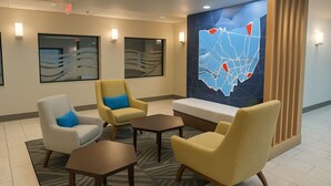 A lobby with a seating area, a map on the wall, and a reception desk. - Holiday Inn Express & Suites Alliance by IHG (Alliance)