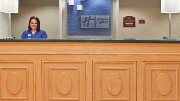 Un comptoir d’accueil d’hôtel avec une enseigne « Holiday Inn Express », une plaque nominative et une plaque commémorative.