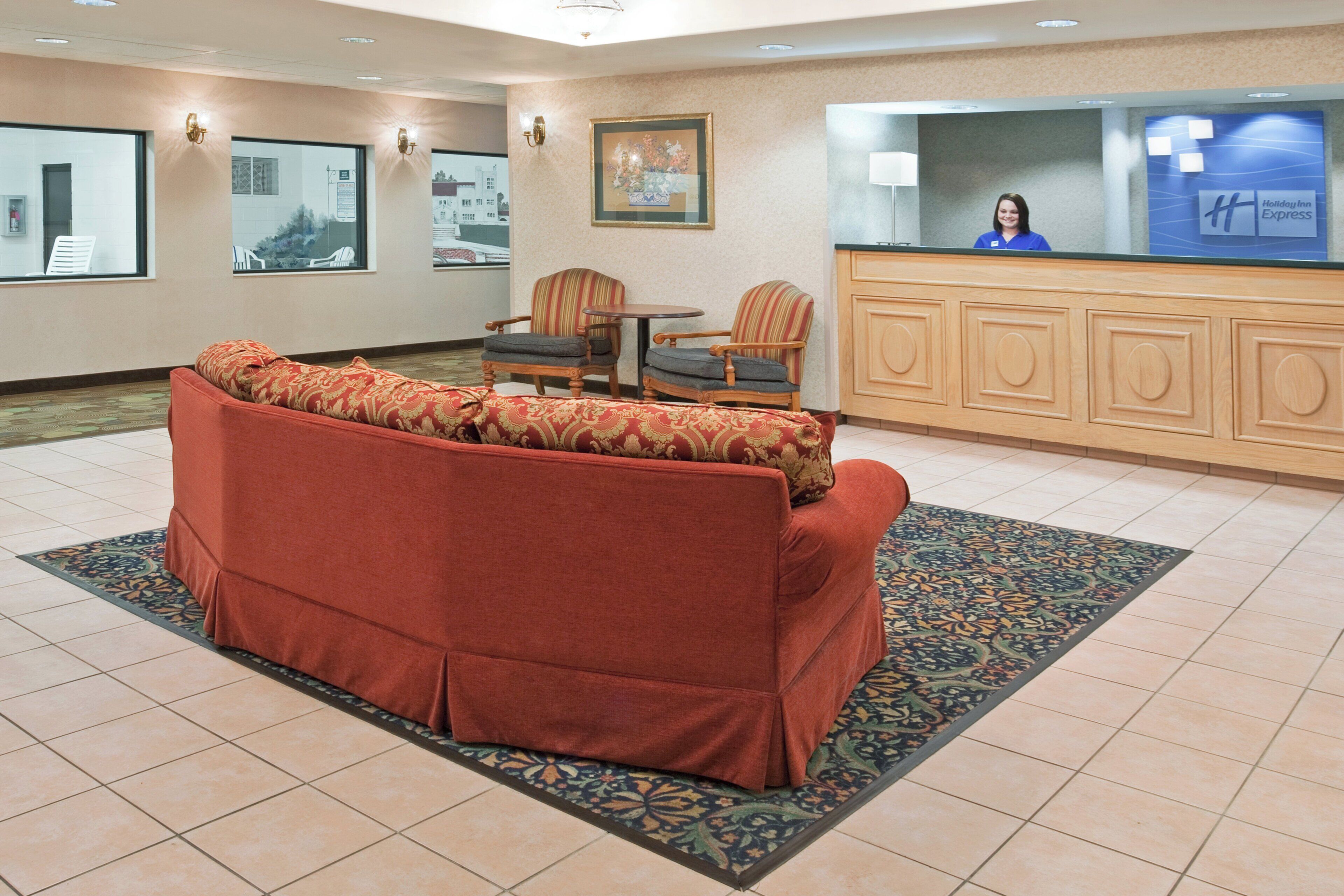 A hotel lobby with a red sofa, a reception desk, and a patterned rug.