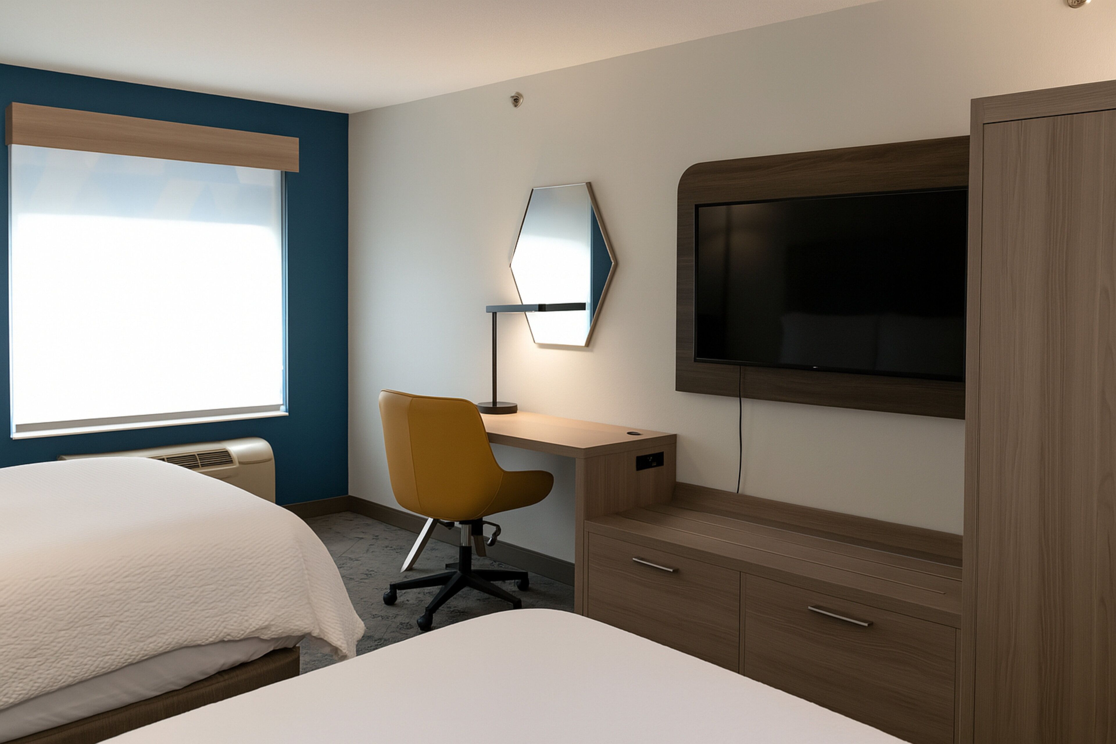 Habitació d'hotel amb llit, escriptori, cadira, televisió i armari.