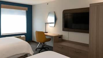 Habitació d'hotel amb llit, escriptori, cadira, televisió i armari.