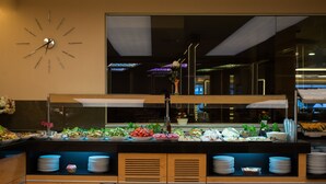 A buffet area with a clock on the wall, a large window, and various food items displayed. - Prestige Hotel Old City (Istanbul)
