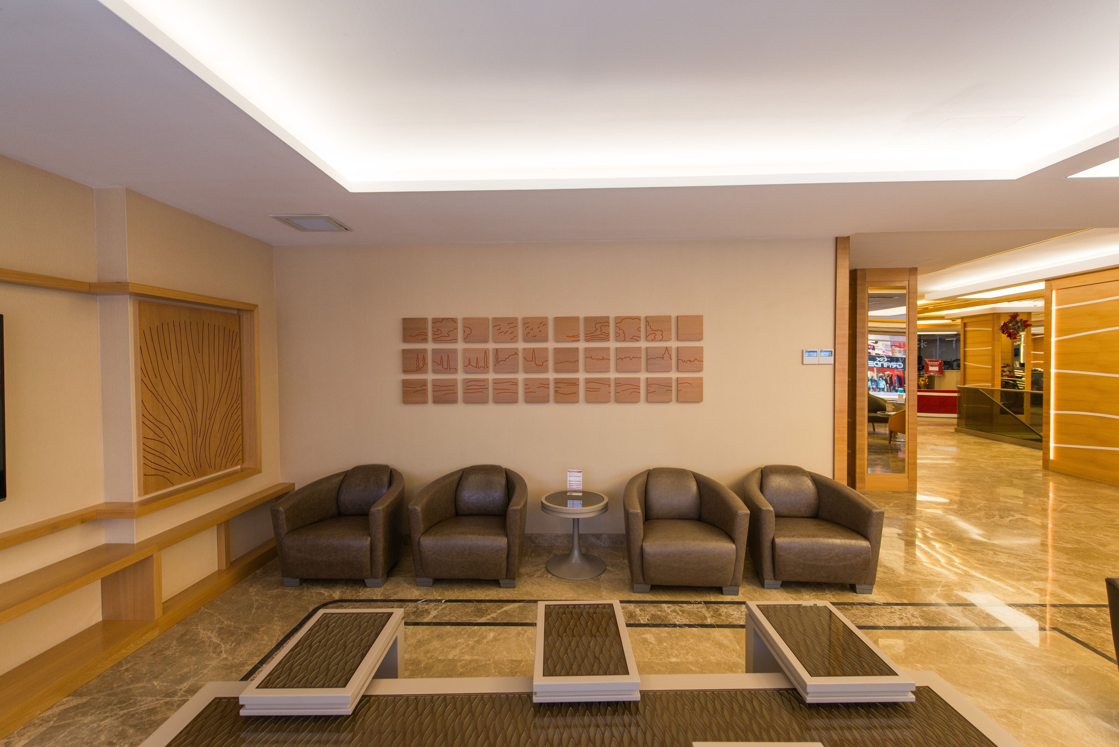 Un vestíbulo con tres sillones de cuero, una mesita redonda y una pared decorada con obras enmarcadas.