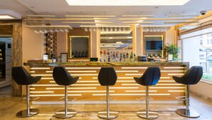 A modern bar area with a wooden counter, three black bar stools, and a variety of bottles and glasses. - Prestige Hotel Old City (Istanbul)