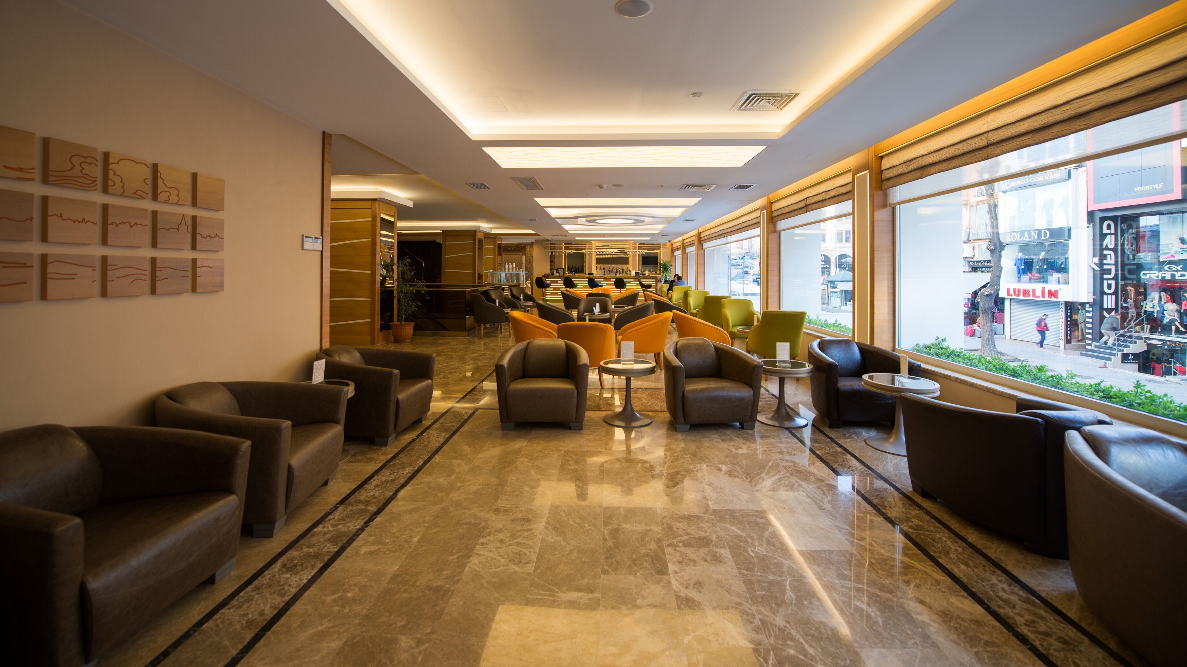 A modern lobby with leather seating, a marble floor, and large windows offering a view of the street.
