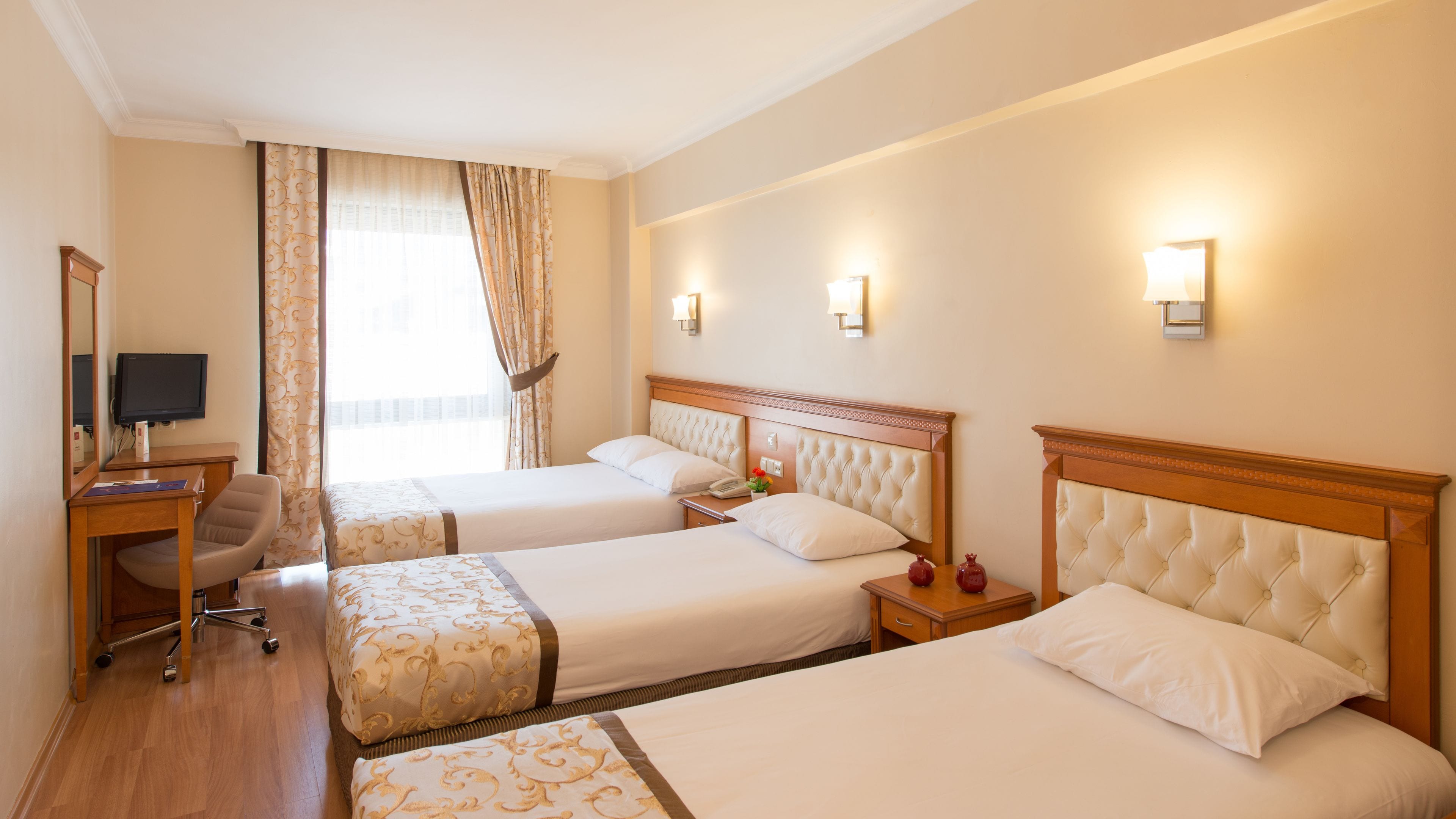 A hotel room with two beds, a desk with a computer, and a chair.