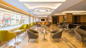 A hotel lobby with a modern design, featuring a mix of seating areas, a central round table, and a large window offering views of the street. - Prestige Hotel Old City (Istanbul)