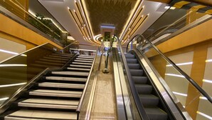 A modern interior with a central escalator flanked by a staircase and glass railings. - Prestige Hotel Old City (Istanbul)