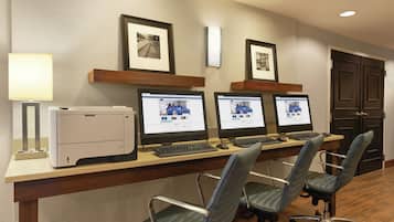 Un mostrador de recepción de hotel con tres monitores de computadora, una impresora y dos sillas de oficina.