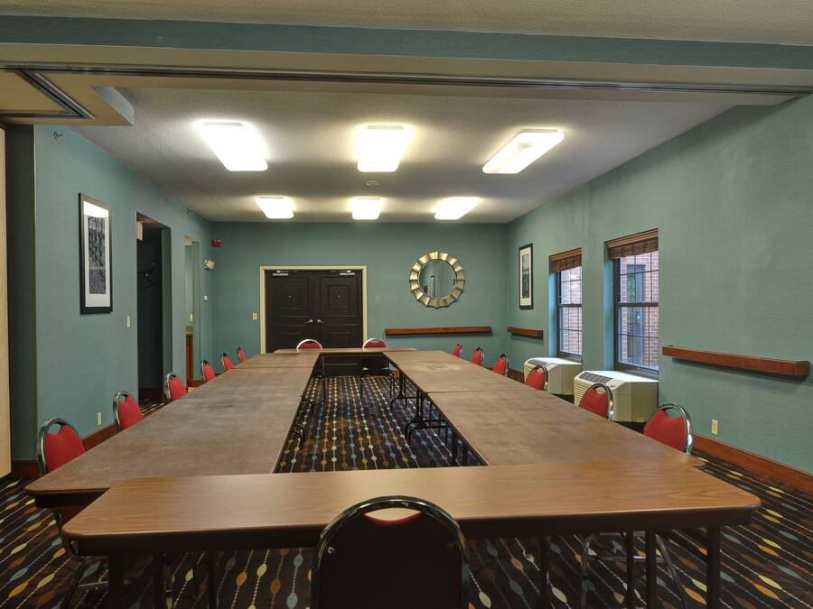 Un salón de conferencias con una larga mesa, sillas y un reloj en la pared.