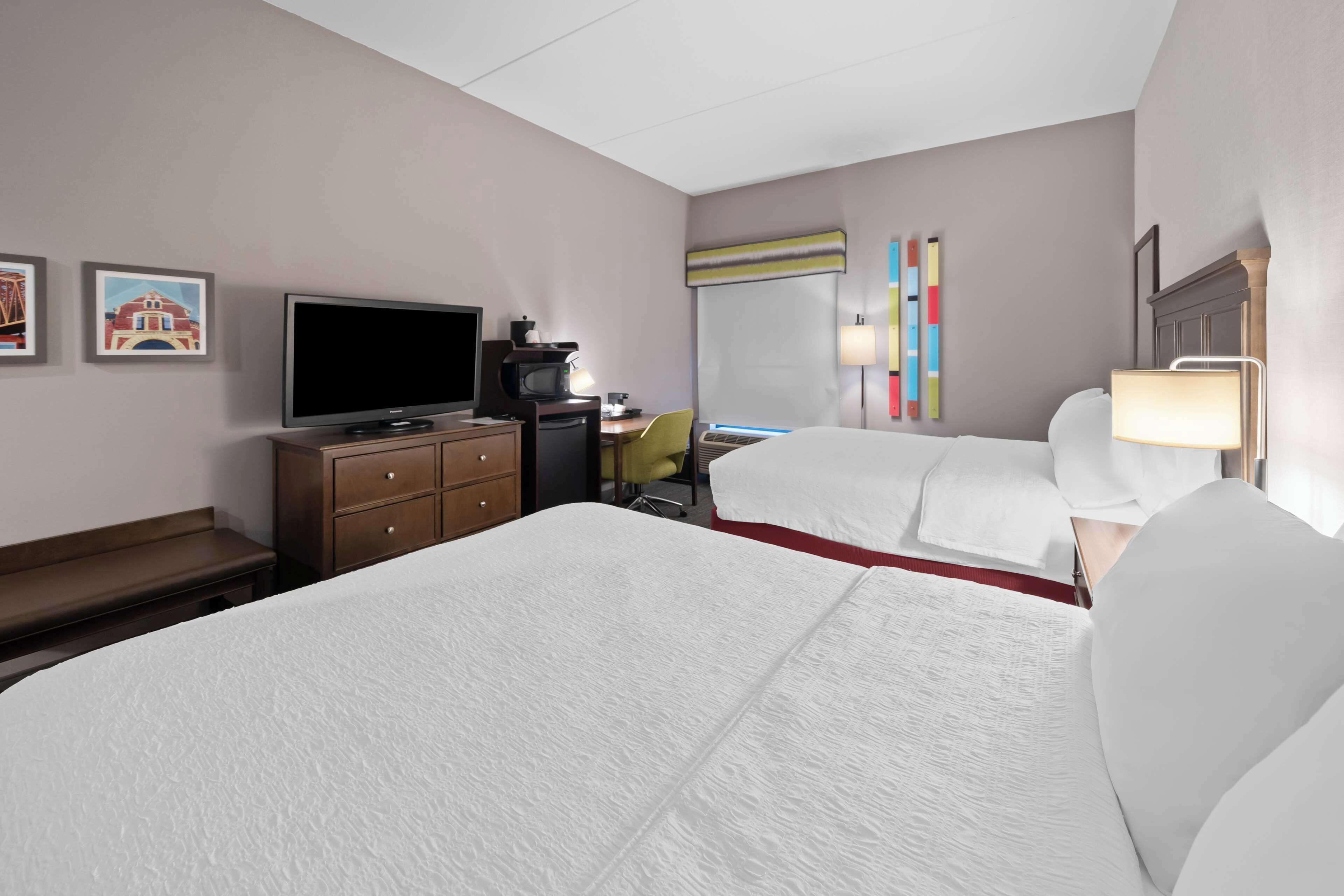 A hotel room with a large bed, a desk with a computer, a television, and a coffee maker.