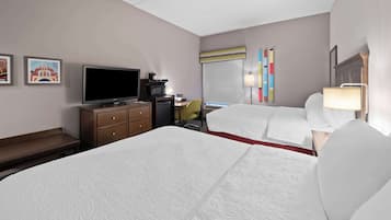 A hotel room with a large bed, a desk with a computer, a television, and a coffee maker.