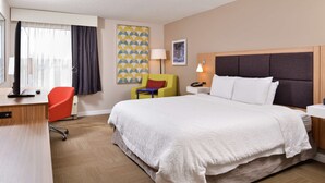 A hotel room with a large bed, a desk with a computer, a chair, and a lamp. - Hampton Inn Greensboro-East (McLeansville)