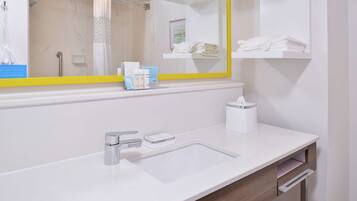 A modern bathroom with a white sink, chrome faucet, and a yellow-framed mirror.