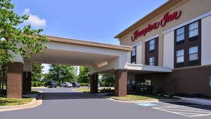 A Hampton Inn hotel entrance with a 'Welcome' sign, covered parking, and a clear sky. - Hampton Inn Greensboro-East (McLeansville)