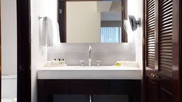 A bathroom with a white sink, a mirror above it, and a towel hanging on the wall.