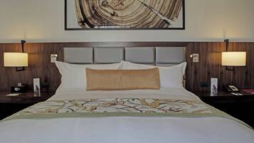 Habitación de hotel con una cama grande, dos lámparas de noche, un cabecero y una obra de arte colgada en la pared.
