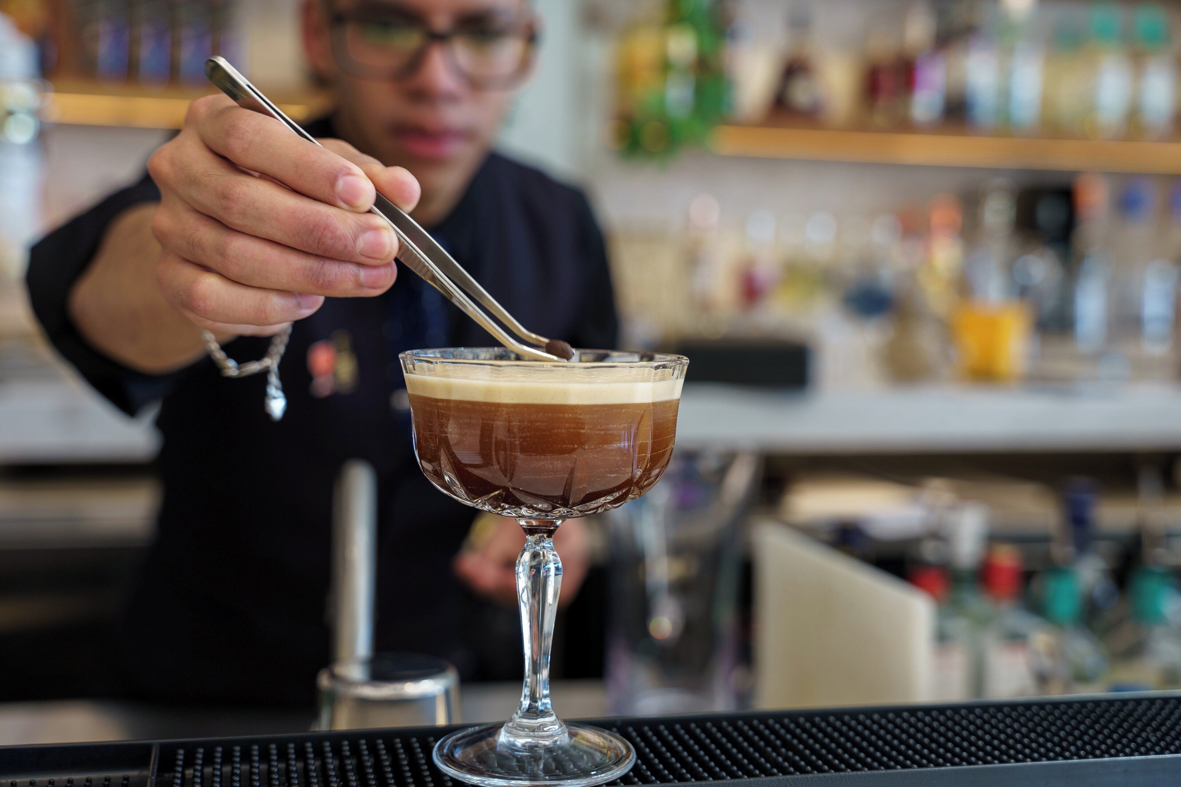 A bartender stirring a cocktail in a glass.