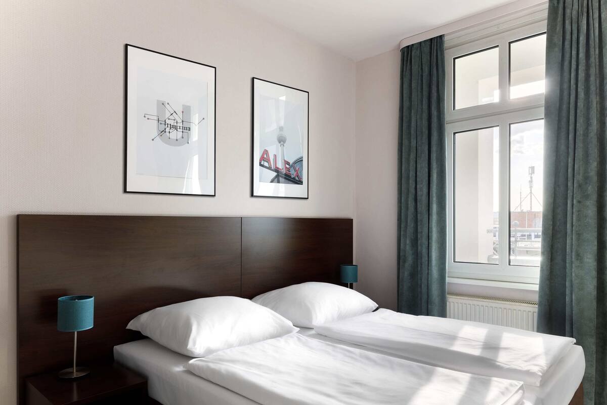 Une chambre d’hôtel avec un grand lit, deux tables de chevet, une tête de lit et deux tableaux encadrés accrochés au mur.