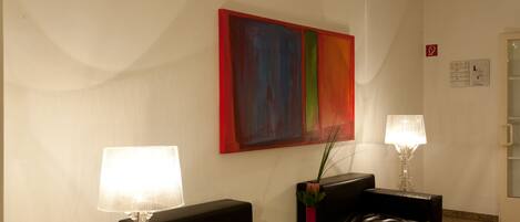 A modern lobby with a black leather sofa, a white table, and a colorful abstract painting on the wall.