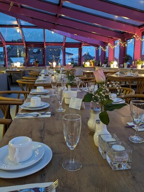 Ein Restaurant mit gedeckten Tischen, ausgestattet mit klarem Glasgeschirr und floralen Tischdekorationen.