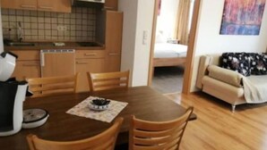 A compact living space with a kitchenette, a dining area with a wooden table and chairs, and a sofa in the living area. - To Be Deleted - Hotel Princess (Rodenbach)