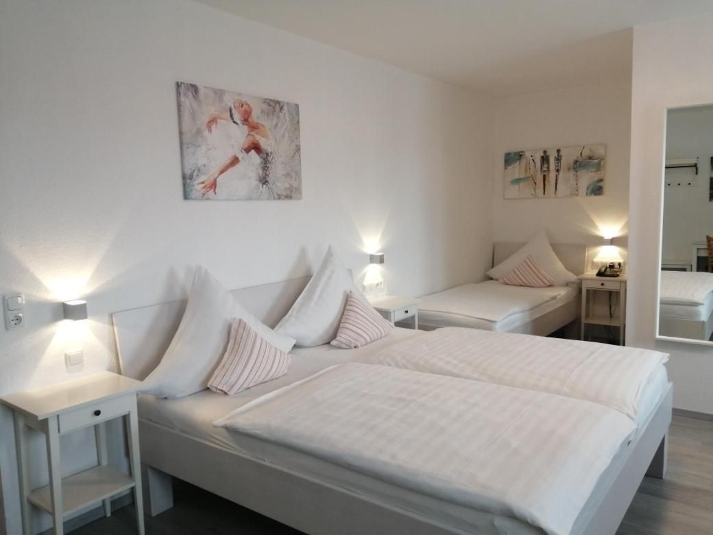 Une chambre d’hôtel avec deux lits, des tables de chevet, des lampes fixées au mur et des œuvres d’art.