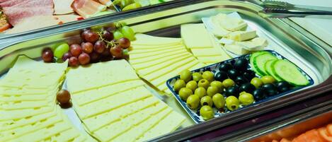 Un bufé con diversos alimentos, incluyendo queso, carnes y frutas.