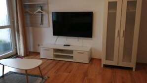 A room with a flat-screen TV mounted on a white cabinet, a small white table, and a wardrobe with glass doors. - To Be Deleted - Hotel Princess (Rodenbach)