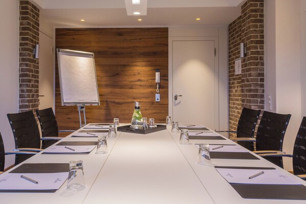 A conference room with a long table, chairs, a flip chart, and a projector.