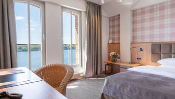 Een hotelkamer met een bed, een bureau, een stoel en uitzicht op een meer.