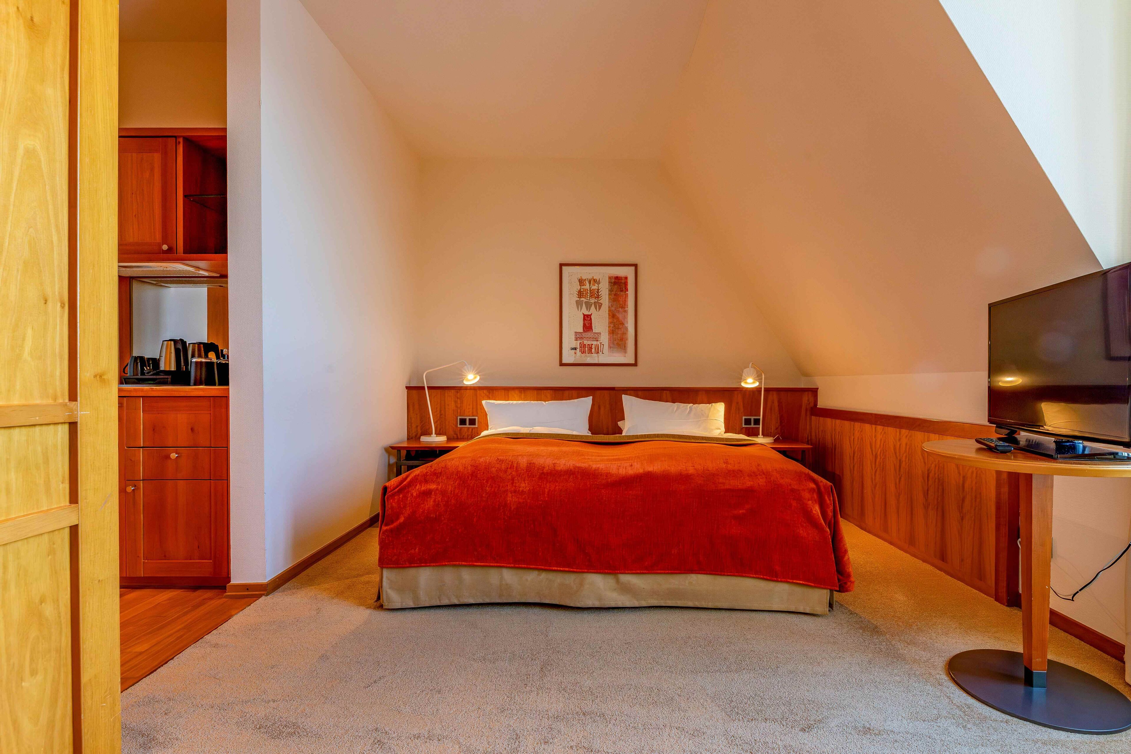 Un dormitorio con una cama, un televisor, un armario de madera y un cartel en la pared.