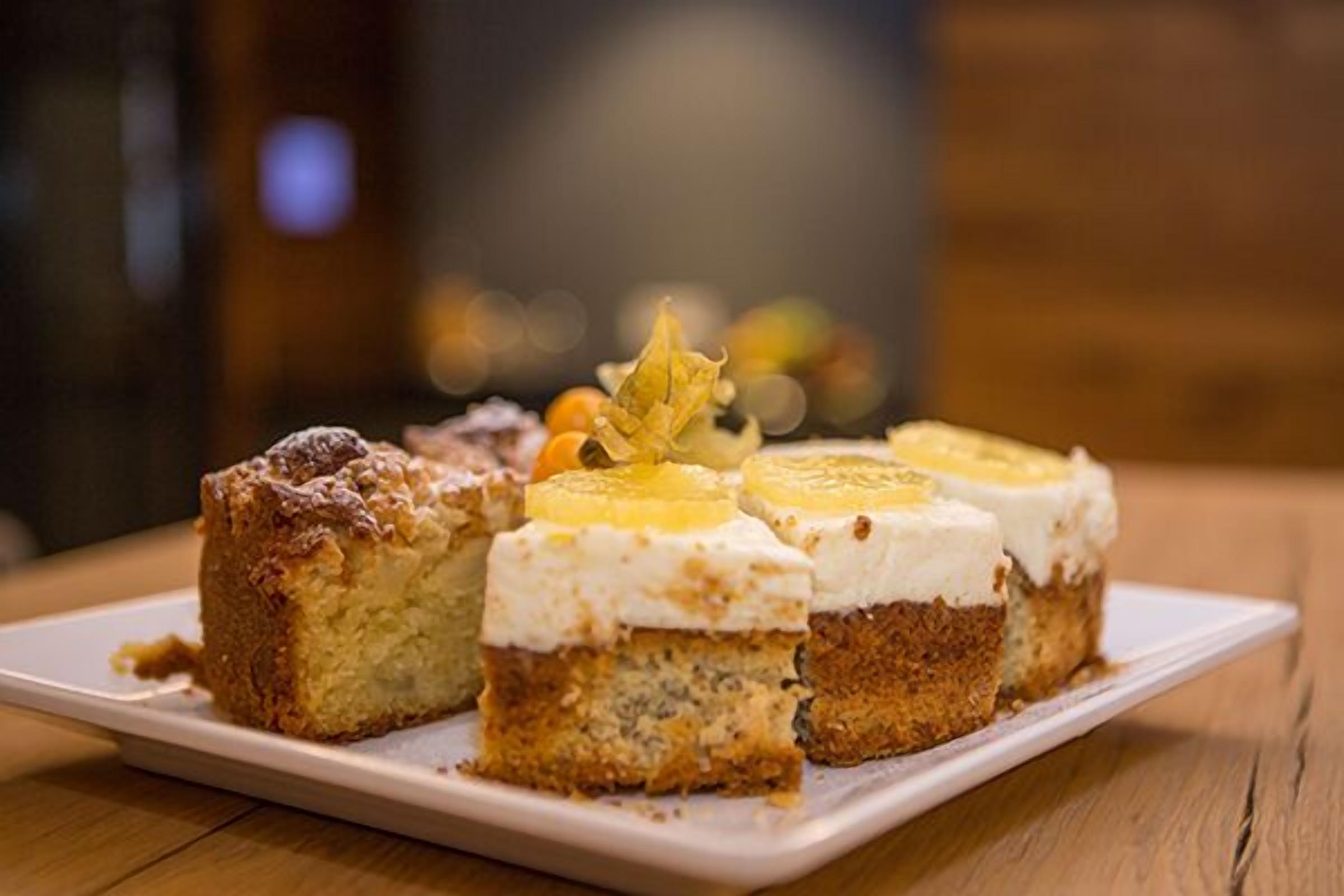 Un plato de postre con tres porciones de pastel sobre una vajilla blanca.