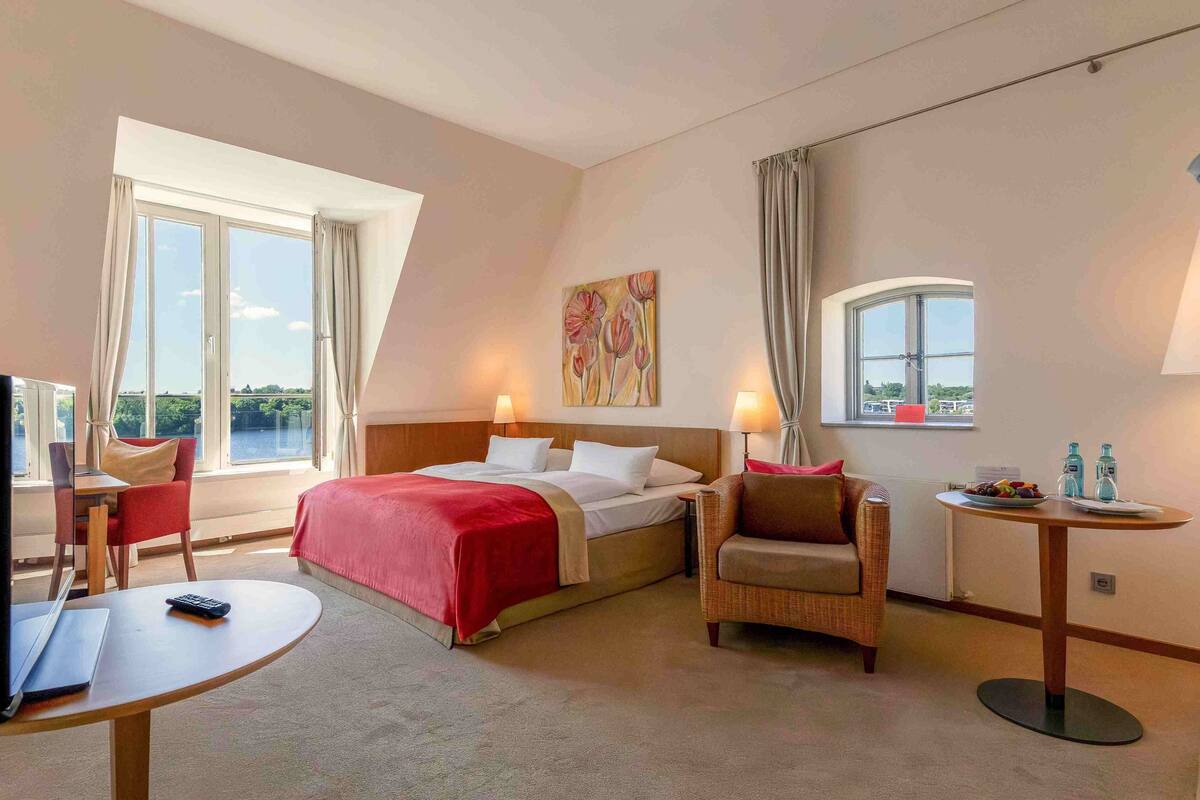 Een hotelkamer met een bed, een bureau, een stoel, een kleine tafel en een raam met uitzicht.