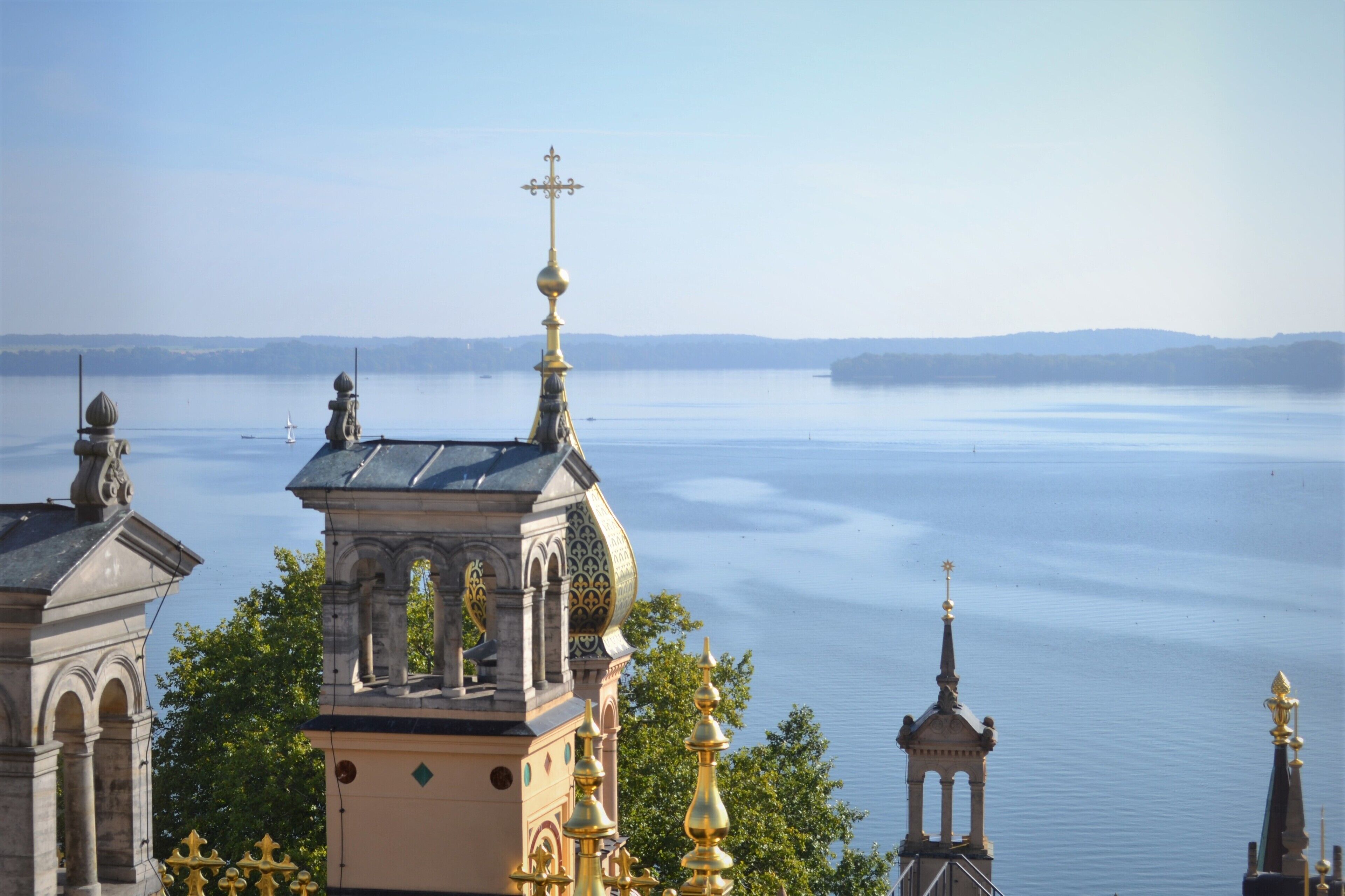 A view of a waterfront building with ornate architecture, including domes and spires, overlooking a calm body of water.
