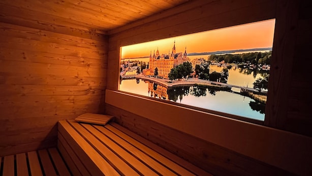 Een houten hutje met een bankje en een raam met uitzicht op een kasteel en een meer.